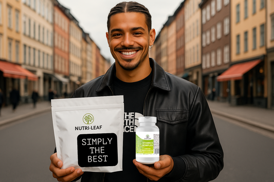 Smiling man standing on a European city street holding a Nutri-Leaf Vitamin B Komplex bottle in one hand and a branded Nutri-Leaf pouch labeled “Simply the Best” in the other, promoting natural supplements and daily wellness.